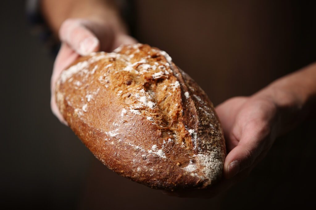 male hands holding freshly baked rye bread closeup