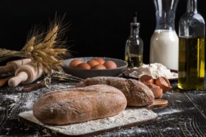 beautiful still life with different kinds bread grain flour weight ears wheat pitcher milk eggs black background